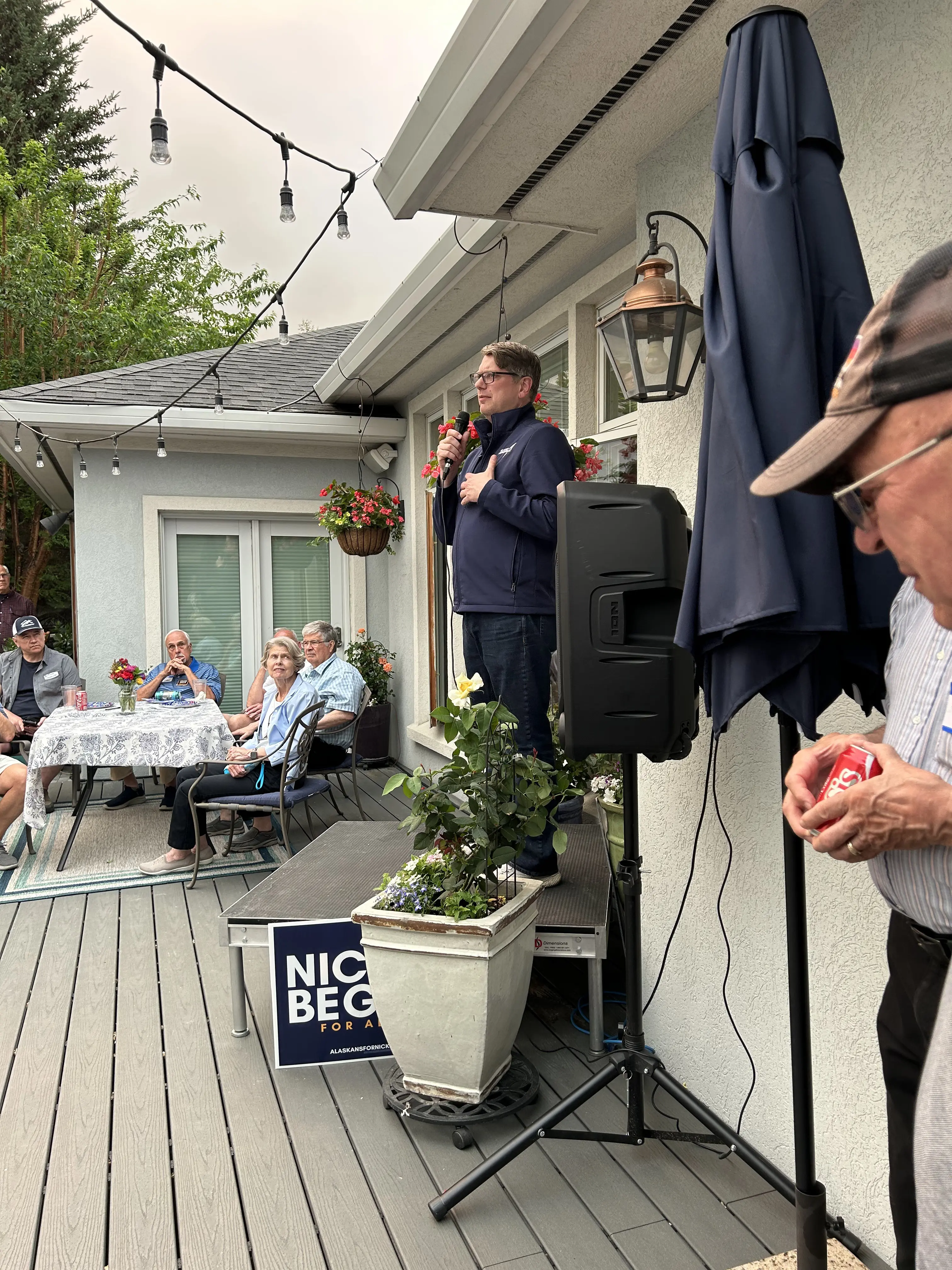 Supporters at an outdoor campaign event on a porch
